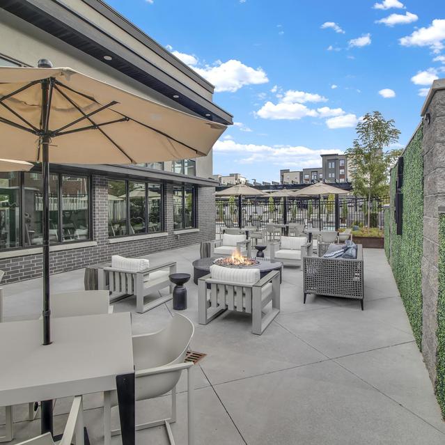 Ember Peaks at American Fork - Outdoor Living Space with Umbrella and View of Apartment Building